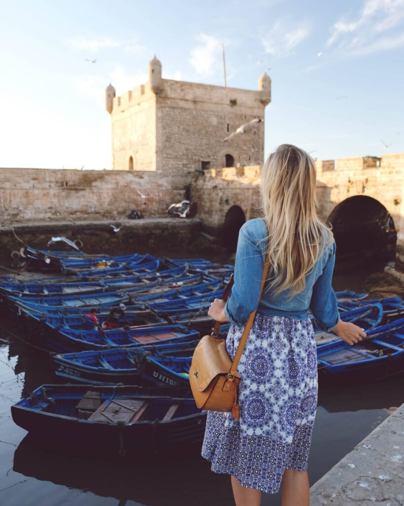 A woman stand beside a group of boat durin her day trip to Essaouira within the best day trips from Marrakech